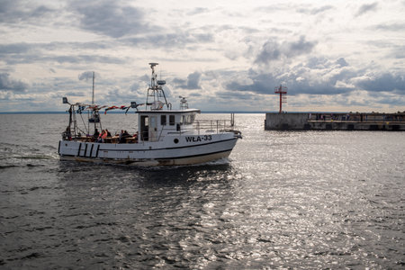 Hel, Pomeranian, Poland - 07.25.2023: A small ship enters the port of the city of Hel, summer day, cloudy.のeditorial素材