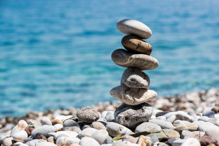 Stones stacked in a pyramid on a sunny day on a pebble beach, blurred background. Mediterranean Sea.の写真素材