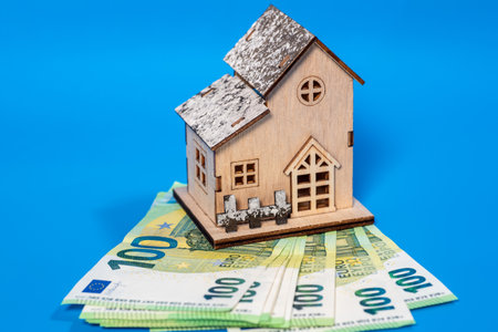 A house model stands on euro banknotes on a blue background, selective focus. Mortgage loan or bill payment concept.の写真素材