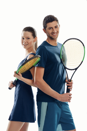 Cheerful tennis players on white. Woman and man smiling and holding racquets, posing for a photo before the match.の写真素材