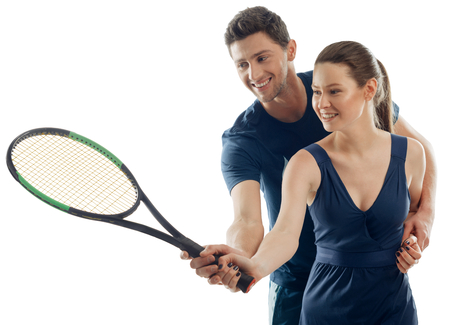 Woman learns playing tennis with help of a male coach. Joy of physical activity, sport games, skills.の写真素材