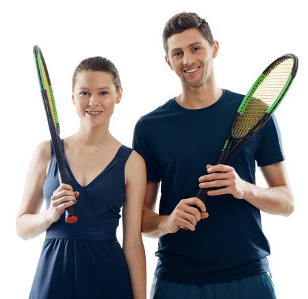 Sportive couple posing with racquets, wearing team uniform and smiling. Studio shot of professional tennis players.の写真素材