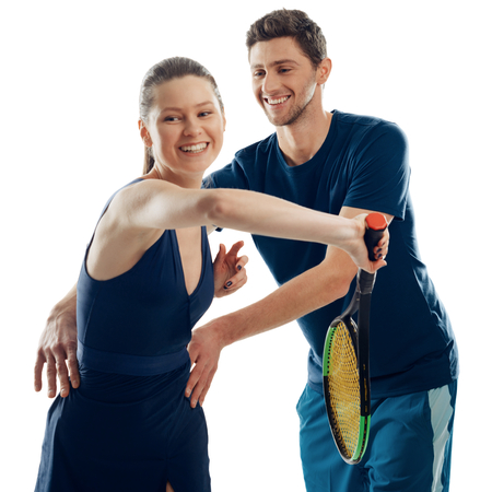 Woman learning to play tennis. Friendly male coach directs her body and teach how to swing a racquet.の写真素材