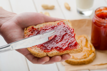 Spreading strawberry jelly on breadの写真素材