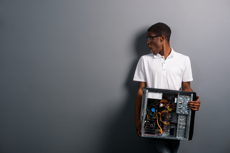 Surprised man holding unscrewed computerの写真素材
