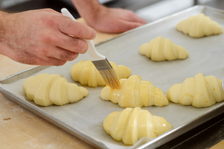 Covering crescent rolls with eggの写真素材