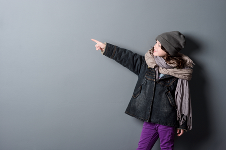 Girl pointing on grey backgroundの写真素材