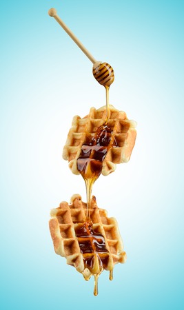 Pouring honey on Belgian wafflesの写真素材