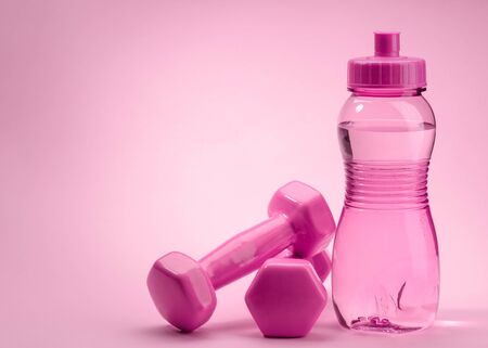 Bottle and dumbbells on pinkの写真素材