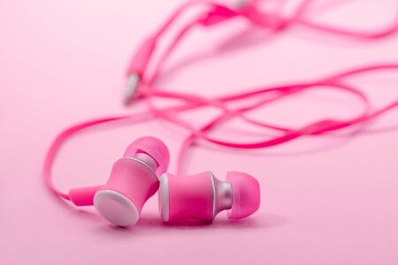 In-ear headphones on pink background
