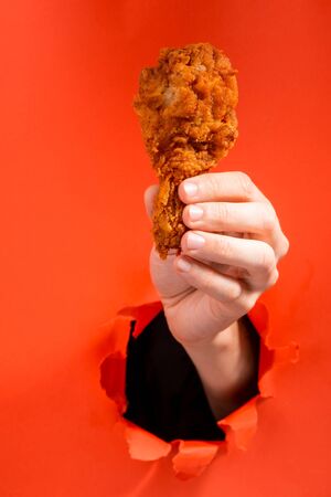 Hand holding a chicken drumstickの写真素材