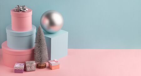 Fir tree, ball, round and square gift boxes on pink and teal backgroundの写真素材