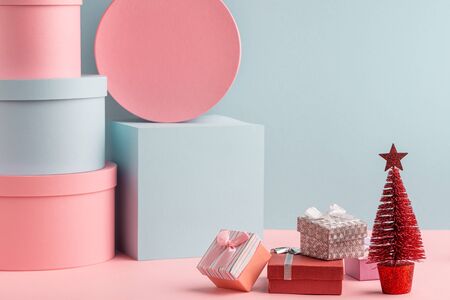 Pink and teal gift boxes and red fir tree on turquoise backgroundの写真素材