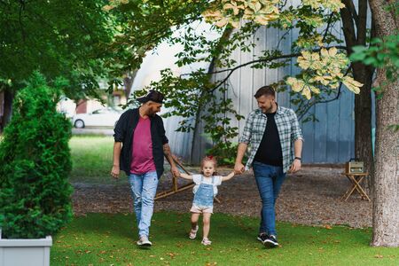 Gay family walking with a little daughter in the parkの写真素材
