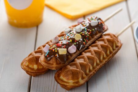 Sweet cornmeal sticks on wooden table. Deep-fried snacks decorated with chocolate, sprinkles and marshmallow.の写真素材
