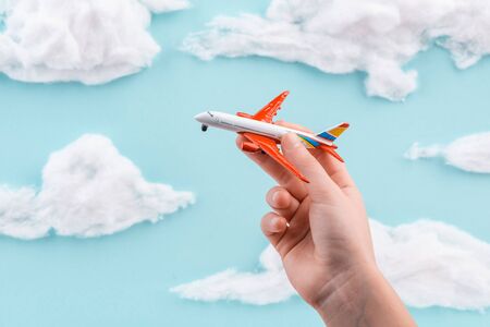 Child playing with toy airplane on handmade blue sky