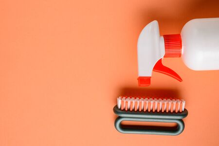 Spray bottle and shoe brush on orange background