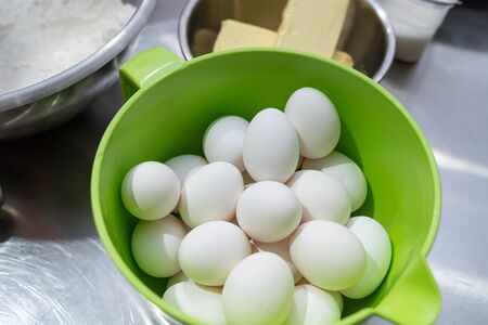 Green plastic bowl with freshly boiled chicken eggs. Cooking food with natural organic ingredients.の写真素材