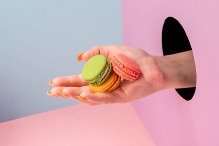 Close-up on womans hand showing colorful macaronsの写真素材