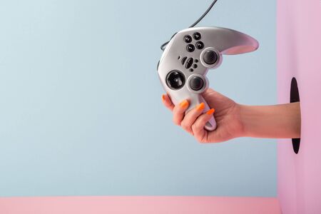 Womans hand holding a silver joystick on blue and pink backgroundの写真素材