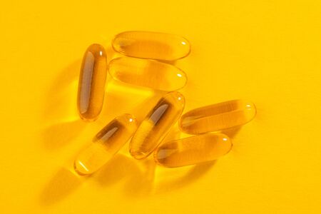 Close-up on cod liver oil capsules on orange backgroundの写真素材