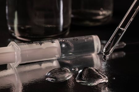 A syringe, few drops and a syringe on dark background