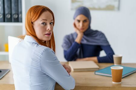 Stressed woman having an interview, sitting in HRs office and looking over
