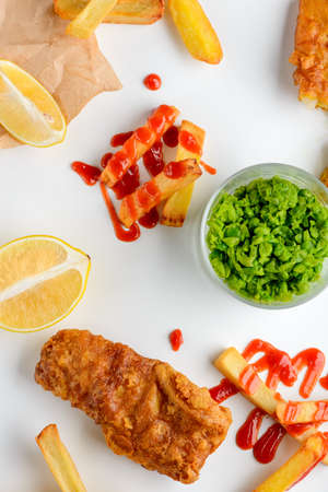 Green peas, lemon slices, fish and chips covered with barbecue sauceの写真素材