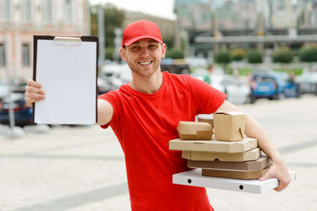 Handsome guy working for delivery service, giving a clipboard to sign the receipt
