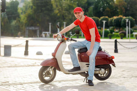 Young man posing with a scooter on the city streetの写真素材