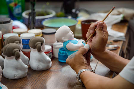 Man painting a Buddha statuette with a thin brushの写真素材