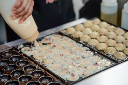 Woman pouring batter into pan with ball-shaped molds