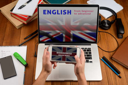 Learning English online. Man opened applications on his phone and laptopの写真素材