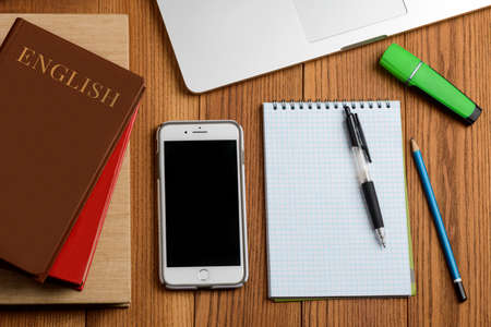 Top view on pupils desktop. Books, smartphone, notepad and other supplies
