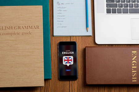 Books and phone on table. Using mobile app to expand vocabularyの写真素材