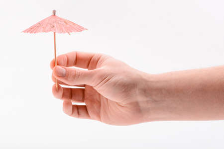 Hand holding a paper umbrella, isolated on whiteの写真素材