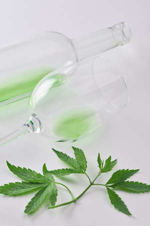 Close-up on empty bottle and glass of hemp-infused wine and leavesの写真素材