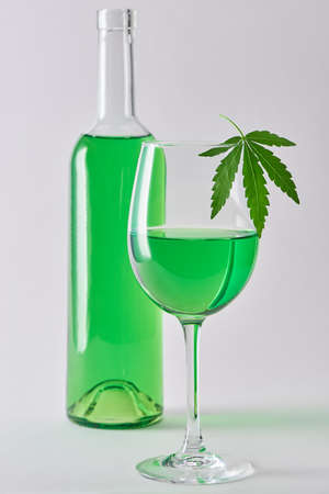 A glass and a bottle of weed wine on white backgroundの写真素材