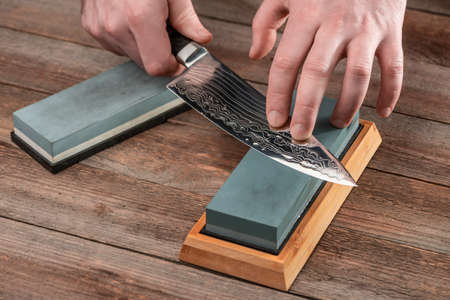 Man sharpening a Japanese chefs knife with a wet whetstone