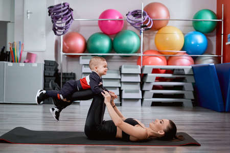 Mother laying on a mat and playing with her kidの写真素材