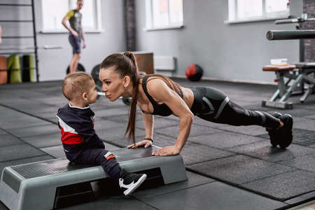 Young fit woman doing push-ups and kissing her little sonの写真素材