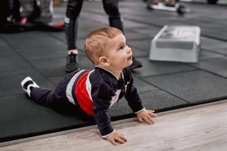 Little kid crawling on the floor while his mother doing exercisesの写真素材