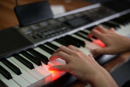 Man playing keyboard with lighting and looking at a display of aの写真素材