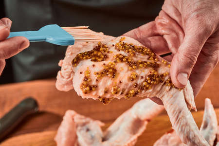 Brushing chicken wings with French mustard, close-up shotの写真素材
