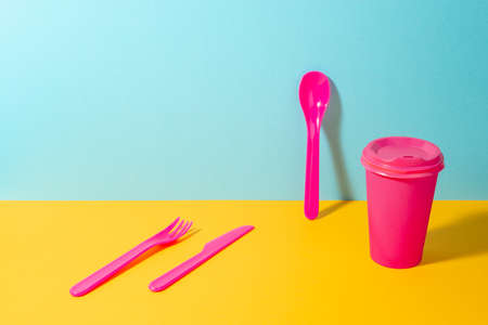 Set of pink plastic fork, knife and spoon, and paper coffee cup