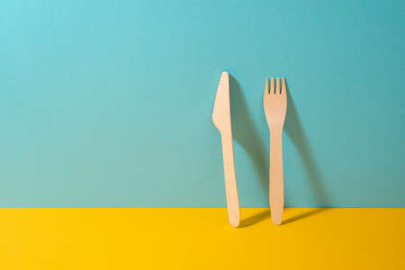 Set of wooden knife and fork on colorful background with copy space