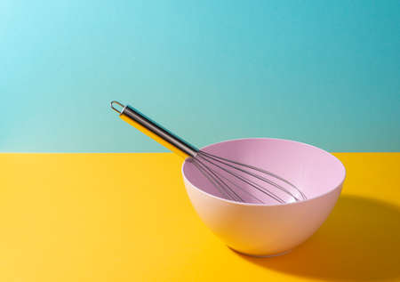 Deep bowl with a whisk on colorful backgroundの写真素材