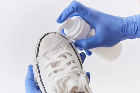 Hands in latex gloves washing a white canvas sneaker with detergentの写真素材