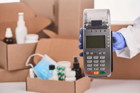 Close-up on a pharmacists hand holding a POS terminalの写真素材