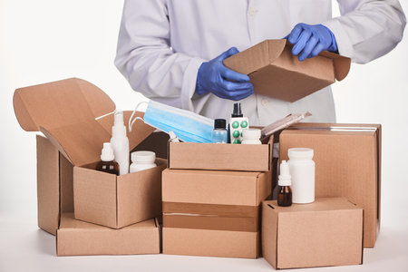 Pharmacist packing ordered medications and supplies into cardboard boxesの写真素材